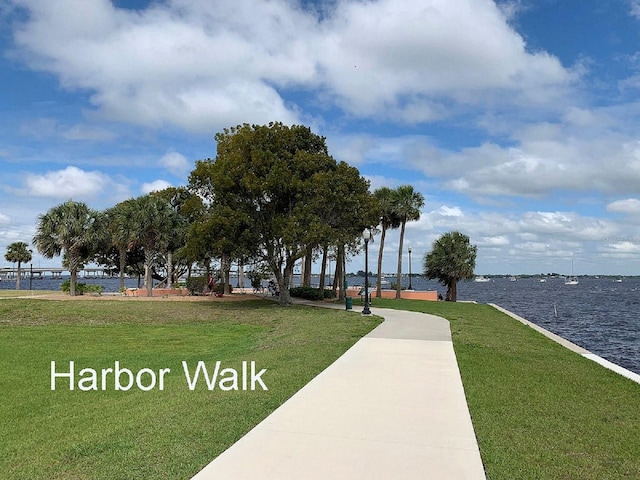 view of property's community with a lawn and a water view