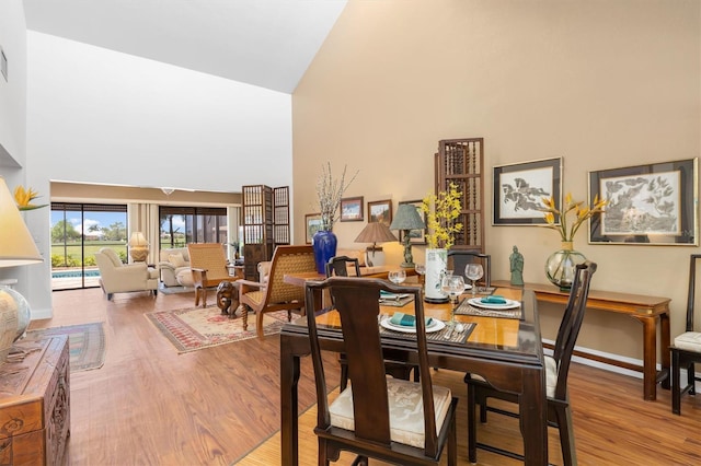 dining area featuring high vaulted ceiling and wood-type flooring