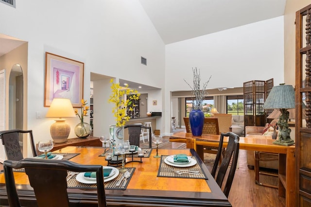 dining space featuring high vaulted ceiling and hardwood / wood-style flooring