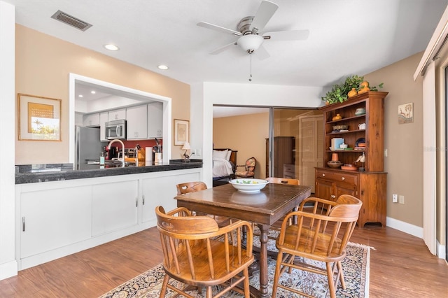 dining area with ceiling fan, sink, and light wood-type flooring