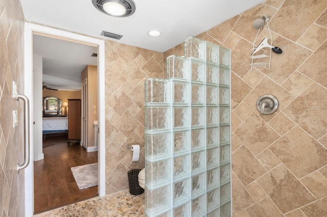 bathroom with hardwood / wood-style floors, toilet, and tiled shower