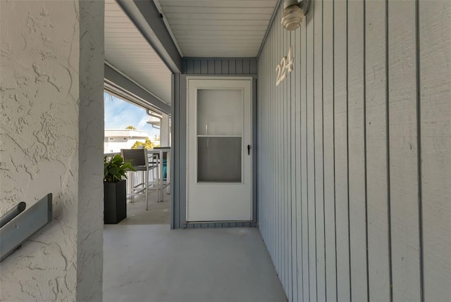 view of exterior entry featuring board and batten siding and a patio