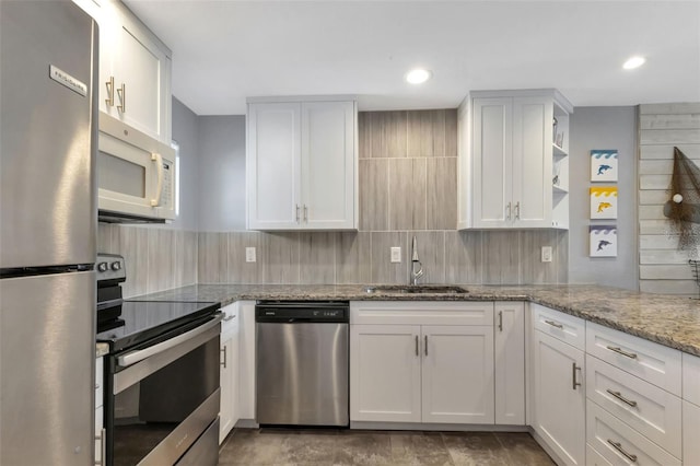 kitchen with white cabinetry, light stone countertops, appliances with stainless steel finishes, and a sink