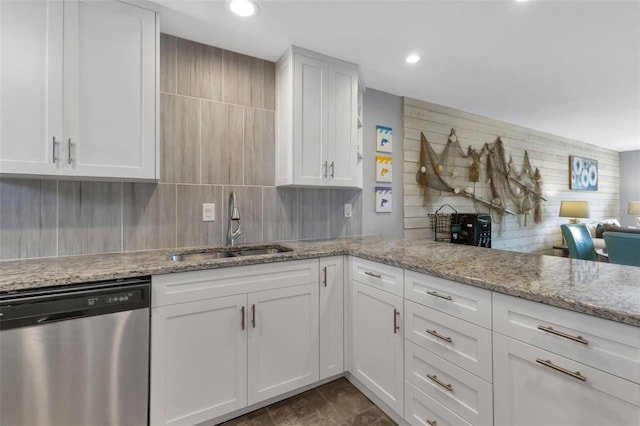 kitchen with tasteful backsplash, sink, light stone counters, stainless steel dishwasher, and white cabinetry