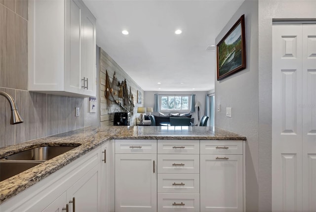 kitchen with white cabinets, backsplash, and light stone countertops