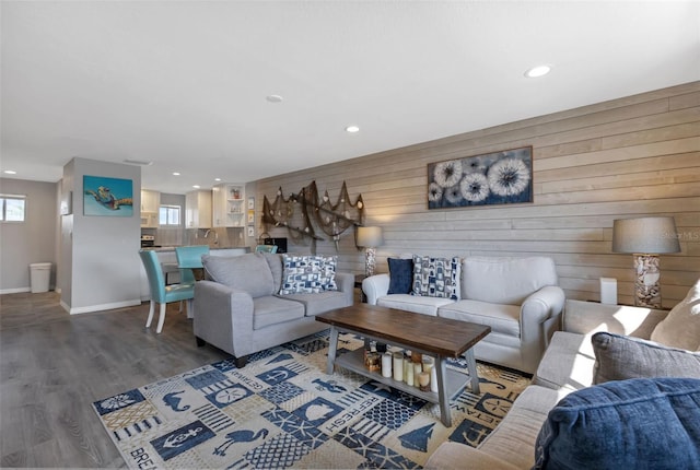 living room featuring plenty of natural light, dark wood-type flooring, and wooden walls