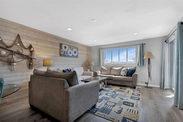 living room with wood finished floors, recessed lighting, wood walls, baseboards, and an accent wall