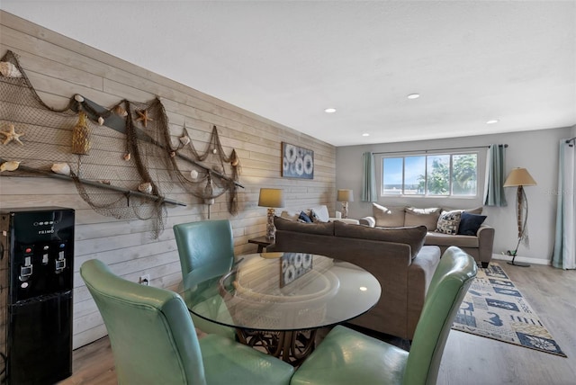 dining area with light hardwood / wood-style floors and wood walls