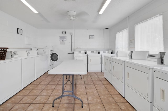 community laundry room featuring light tile patterned floors, independent washer and dryer, and a textured ceiling