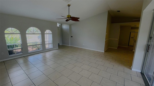 spare room with vaulted ceiling, light tile flooring, and ceiling fan