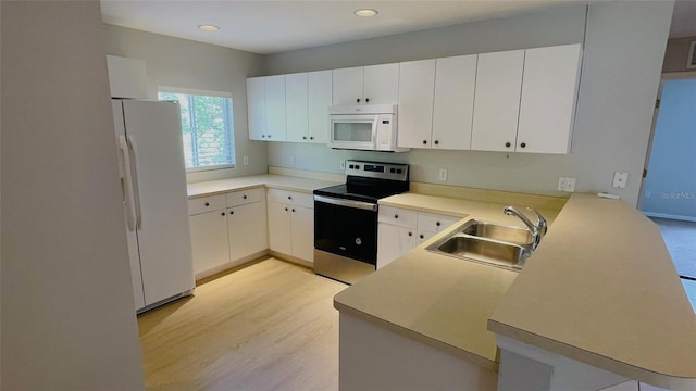 kitchen with kitchen peninsula, light hardwood / wood-style flooring, white appliances, white cabinets, and sink