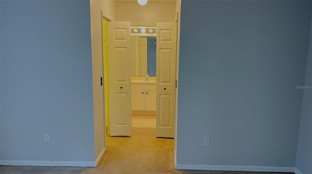 hallway featuring light colored carpet and sink