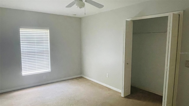 unfurnished bedroom with a closet, light carpet, multiple windows, and ceiling fan