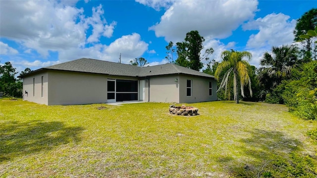 back of property featuring an outdoor fire pit and a yard