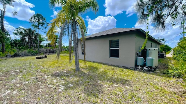 view of side of property with an outdoor fire pit and a yard