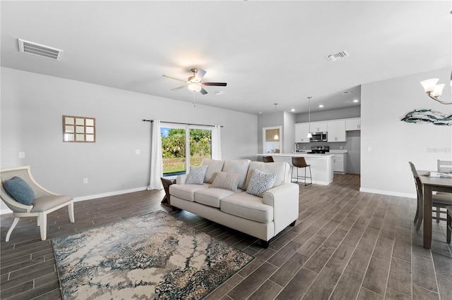 living room with ceiling fan with notable chandelier