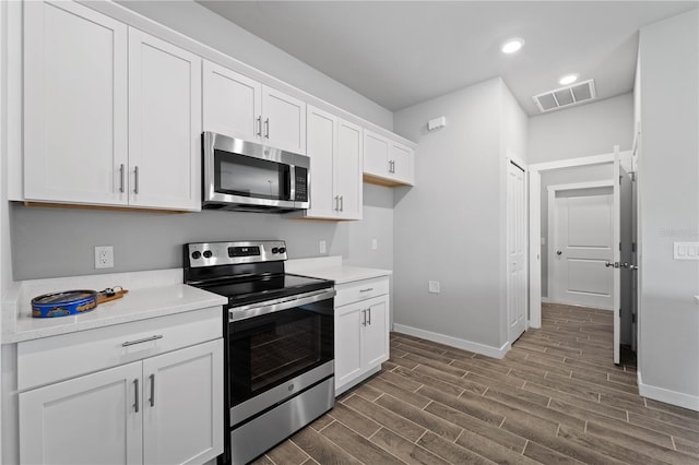 kitchen featuring dark hardwood / wood-style flooring, white cabinets, and stainless steel appliances