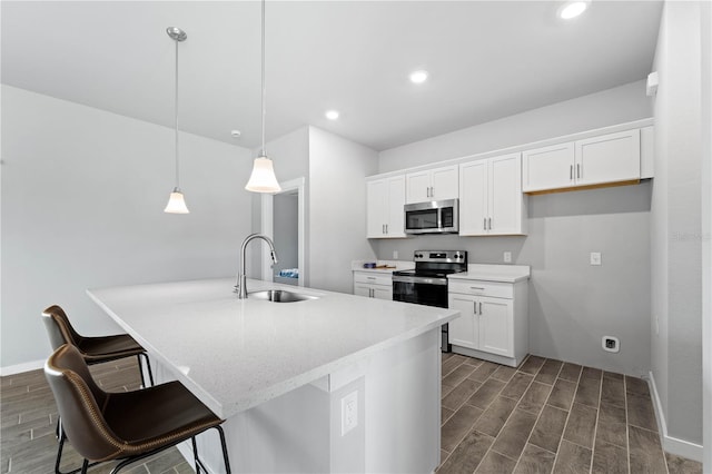 kitchen featuring white cabinetry, sink, hanging light fixtures, a center island with sink, and appliances with stainless steel finishes