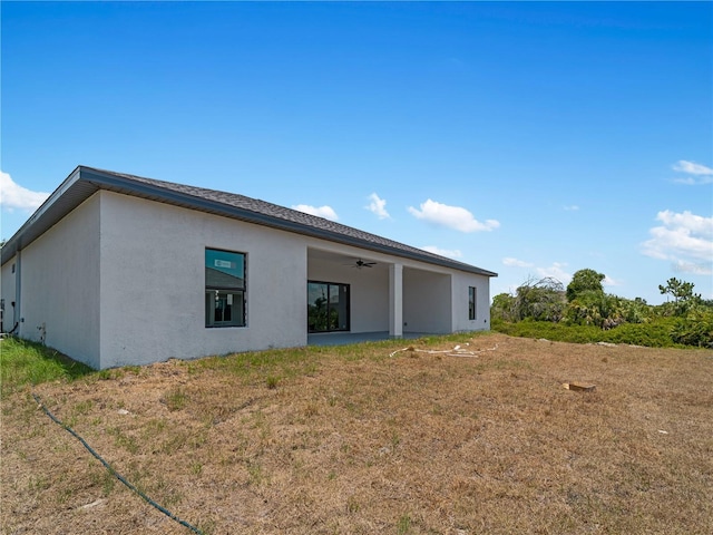 rear view of house featuring a lawn and ceiling fan