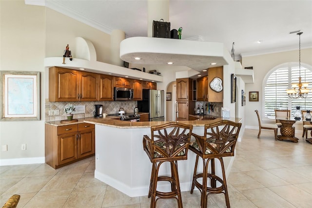 kitchen with pendant lighting, a kitchen breakfast bar, an inviting chandelier, stainless steel appliances, and tasteful backsplash