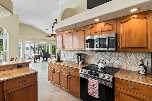 kitchen with backsplash, vaulted ceiling, appliances with stainless steel finishes, and light stone counters