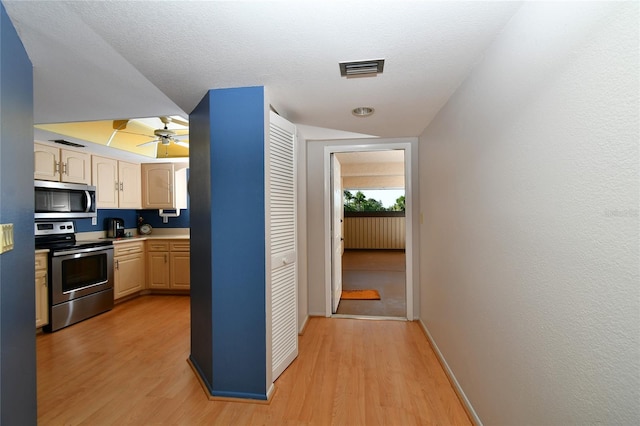 kitchen featuring light brown cabinets, ceiling fan, light hardwood / wood-style flooring, and appliances with stainless steel finishes