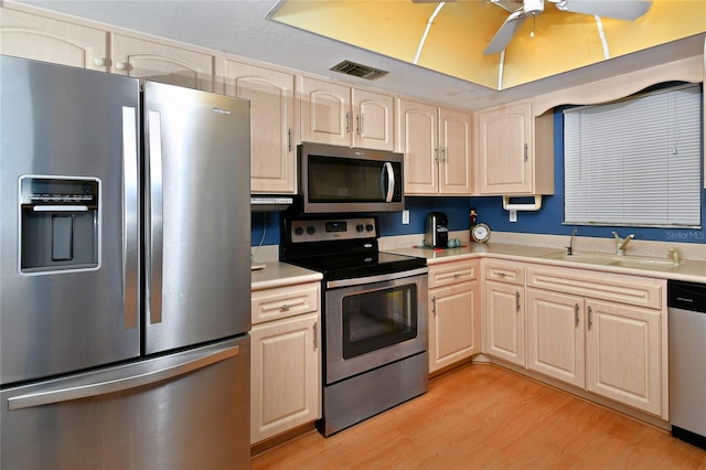 kitchen featuring light hardwood / wood-style floors, ceiling fan, light brown cabinetry, appliances with stainless steel finishes, and sink