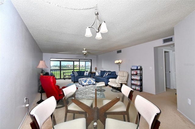 dining area with light carpet, a textured ceiling, and ceiling fan with notable chandelier