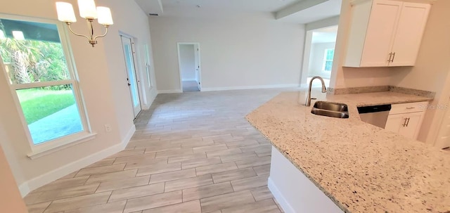 kitchen with sink, white cabinets, stainless steel dishwasher, hanging light fixtures, and light stone countertops