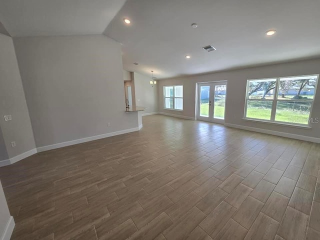 unfurnished living room with a chandelier, lofted ceiling, and hardwood / wood-style flooring