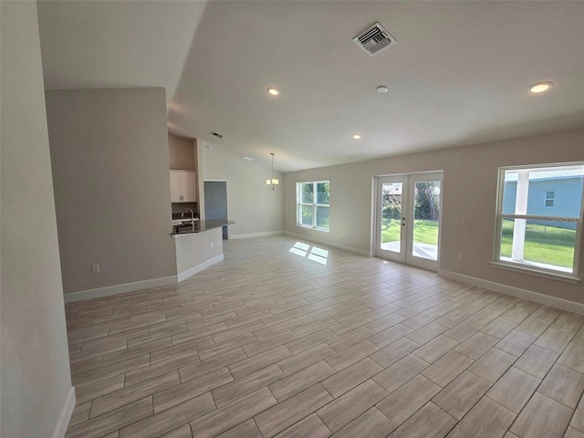 unfurnished living room with french doors, sink, and vaulted ceiling