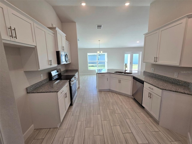 kitchen with a peninsula, appliances with stainless steel finishes, a sink, and white cabinets