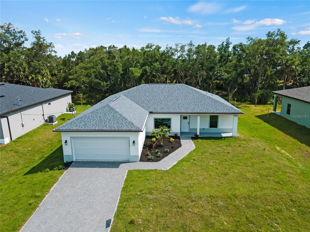 view of front of house with a front lawn, a garage, and central AC