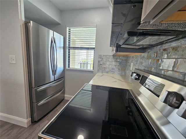 kitchen with backsplash, hardwood / wood-style flooring, range, light stone counters, and stainless steel refrigerator