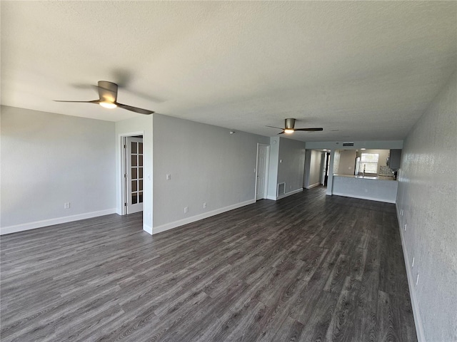 unfurnished living room with a textured ceiling, dark hardwood / wood-style floors, and ceiling fan