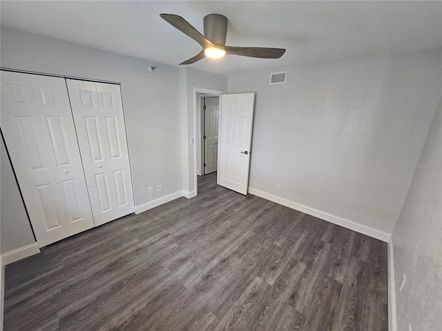 unfurnished bedroom featuring ceiling fan, dark wood-type flooring, and a closet