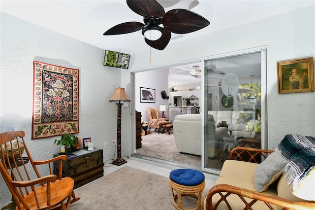 living area with light tile floors and ceiling fan