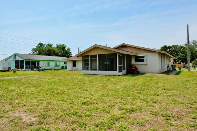 rear view of house with a sunroom and a lawn