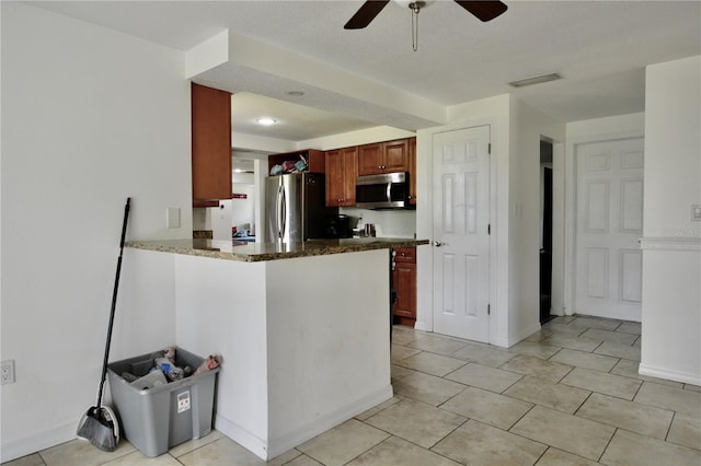 kitchen with appliances with stainless steel finishes, dark stone counters, ceiling fan, and light tile floors