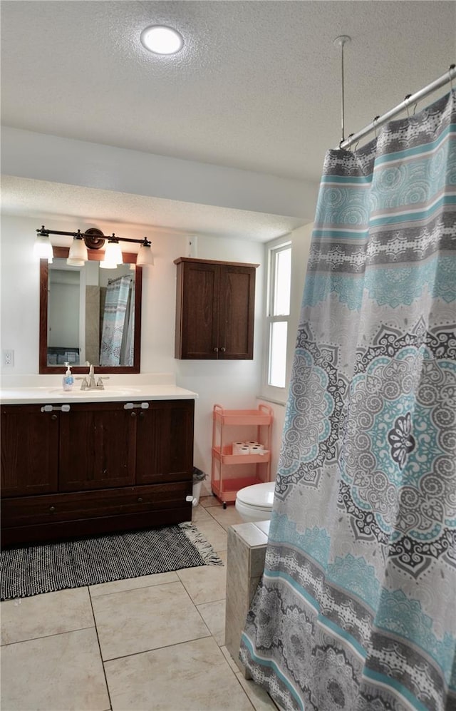 bathroom featuring a textured ceiling, vanity, toilet, and tile flooring