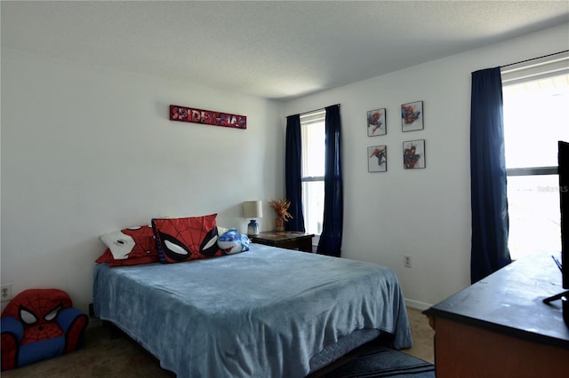 bedroom with dark colored carpet, a textured ceiling, and multiple windows