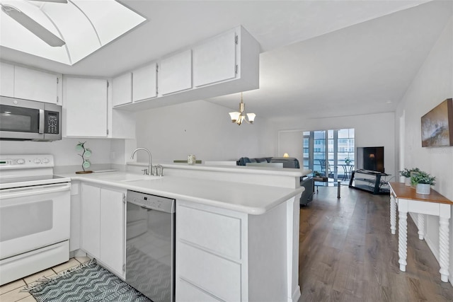 kitchen with kitchen peninsula, appliances with stainless steel finishes, sink, pendant lighting, and white cabinets