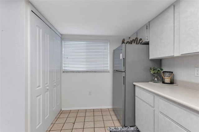 kitchen with backsplash, stainless steel refrigerator, white cabinetry, and light tile patterned flooring