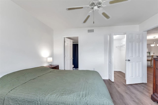 bedroom featuring a walk in closet, hardwood / wood-style flooring, a closet, and ceiling fan