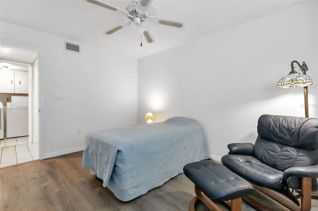 bedroom with ceiling fan, washer and dryer, and hardwood / wood-style flooring