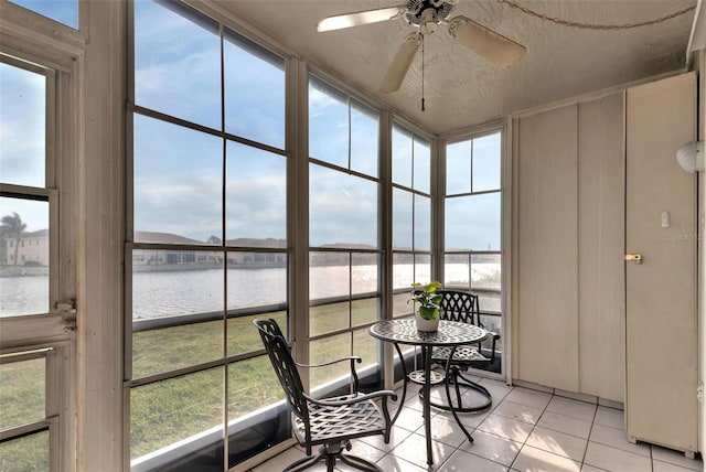 sunroom / solarium with ceiling fan and a water view