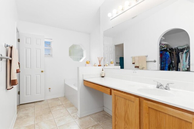 bathroom featuring vanity with extensive cabinet space, tile flooring, and a bath to relax in