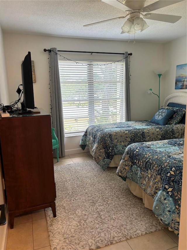 bedroom with a textured ceiling, ceiling fan, and light tile floors