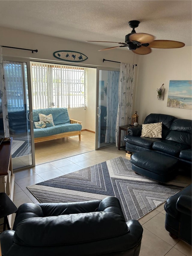 living room with ceiling fan, light tile floors, and a textured ceiling