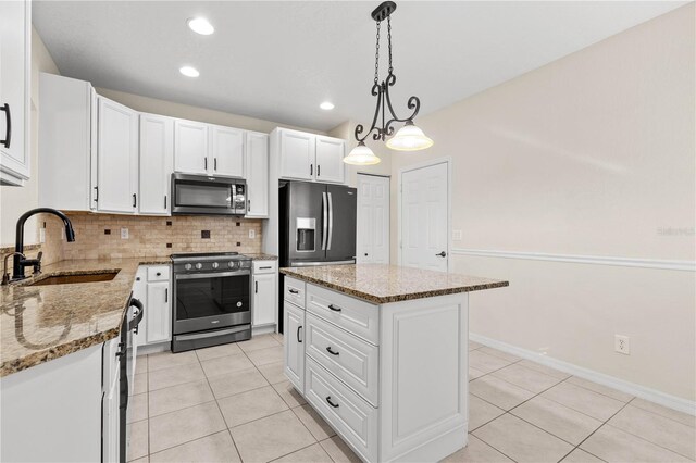 kitchen featuring appliances with stainless steel finishes, backsplash, sink, white cabinets, and a kitchen island